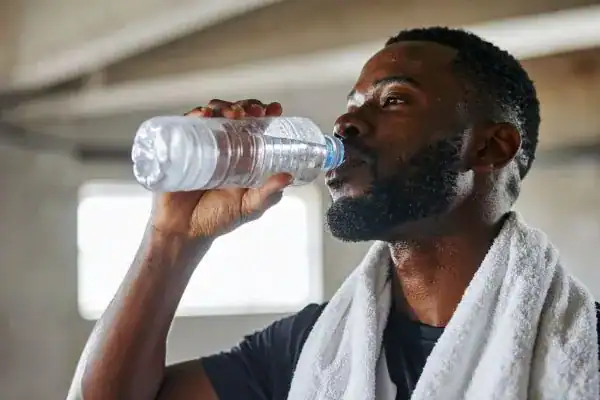 Image of man drinking water to improve hydration Bradford after work out.